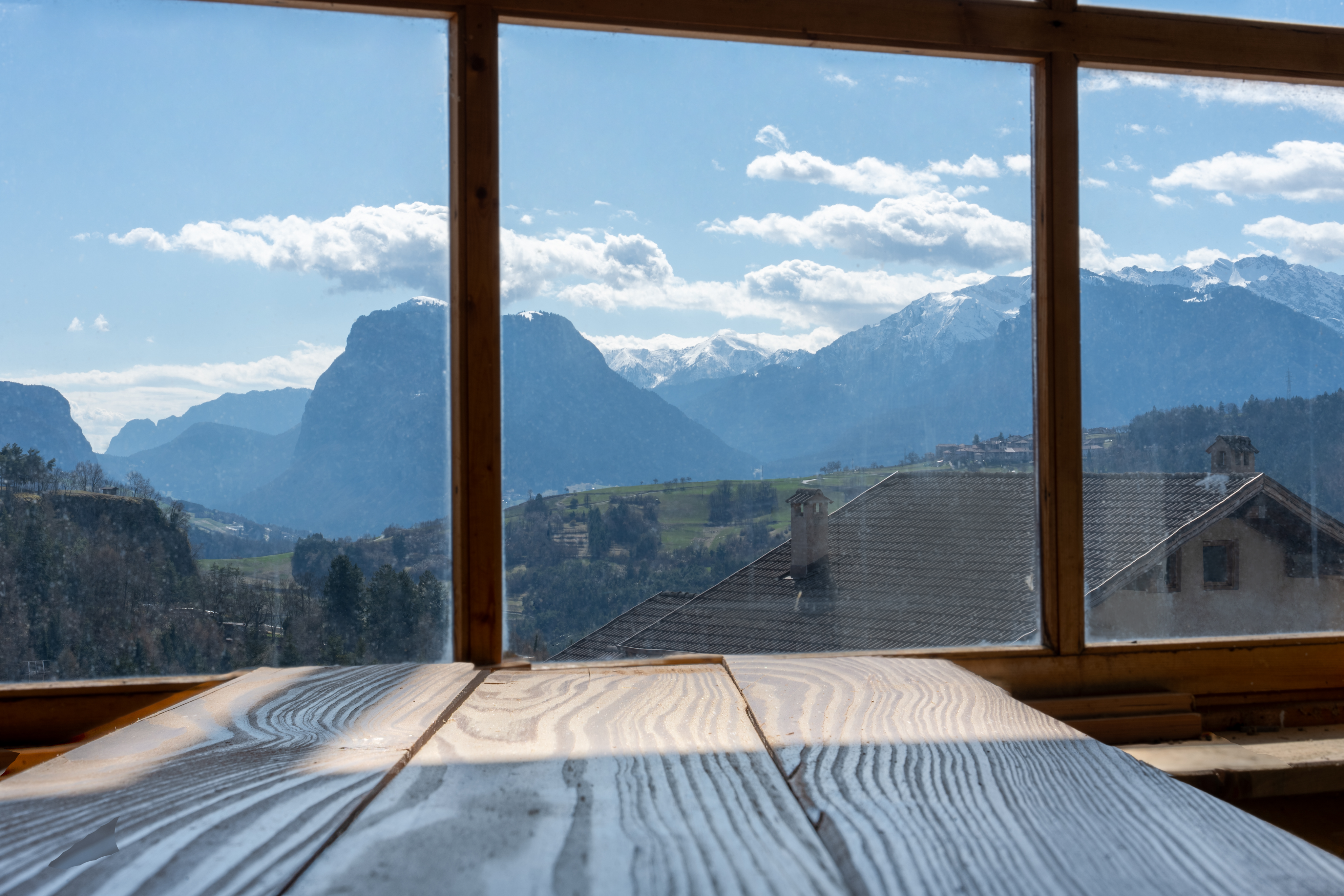 Vista da finestra: montagne innevate delle Giudicarie visibili attraverso serramenti in legno